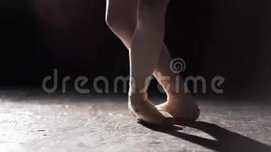 优雅的芭蕾舞演员在她的尖角芭蕾舞鞋上跳舞，在演播室的黑色背景上聚光灯下。 女孩<strong>表演</strong>经典<strong>节目</strong>